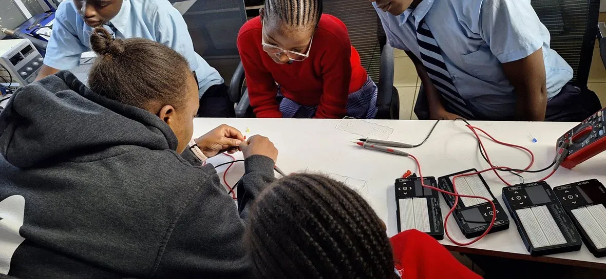 An educator and students wiring circuits together at a bench of UNDA Xplora kits